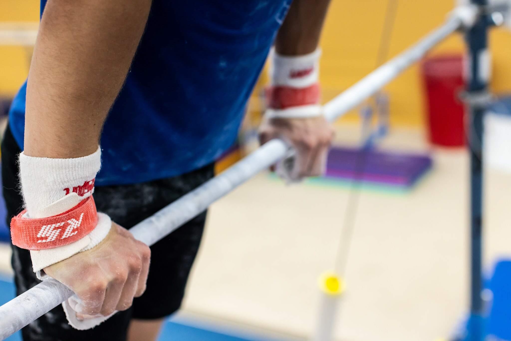 Male gymnast on high bar with Reisport® Men's Elite Protec High Bar Grips on hands