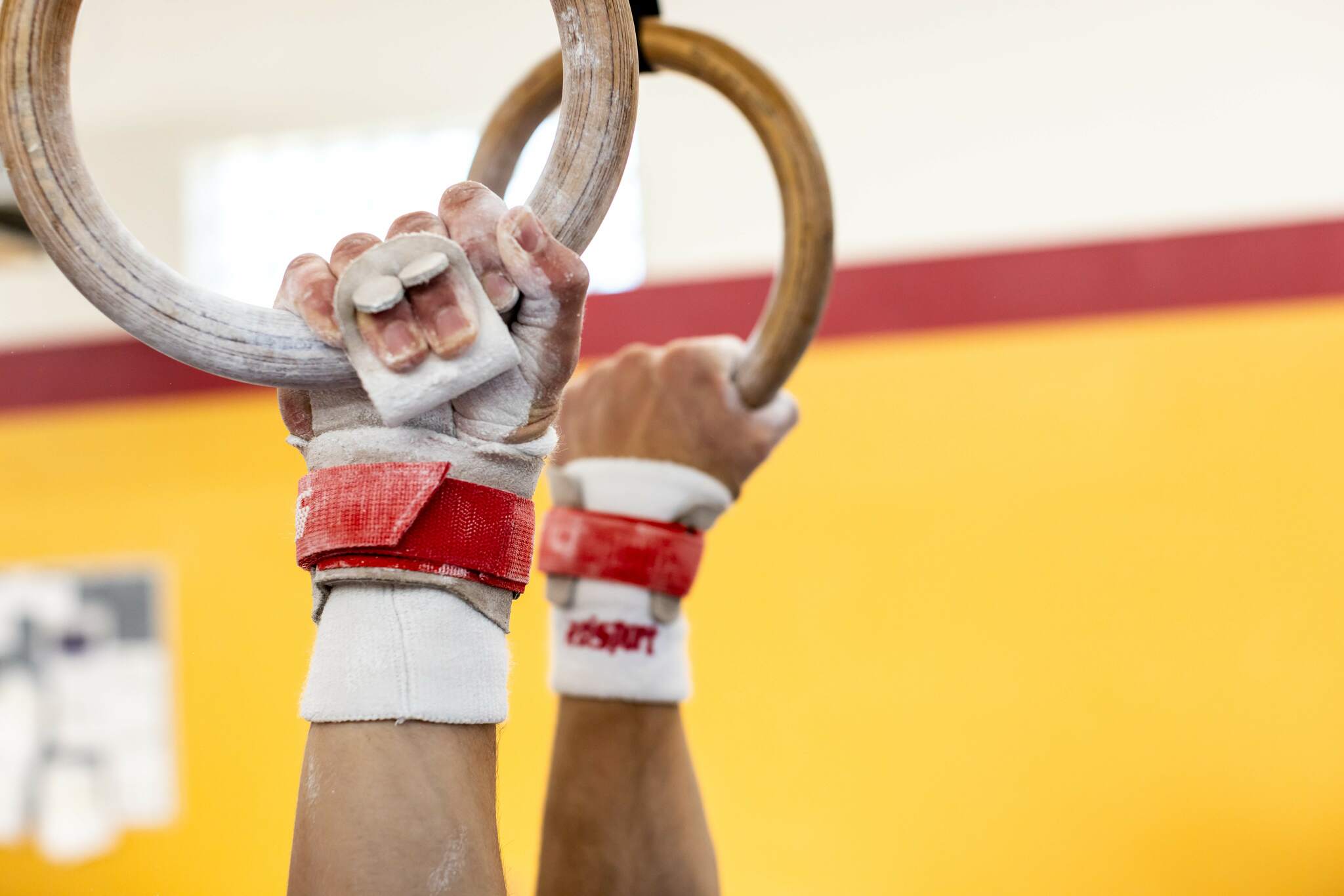 Male gymnast on rings wearing Reisport® Men's Elite Protec Ring Grips on hands