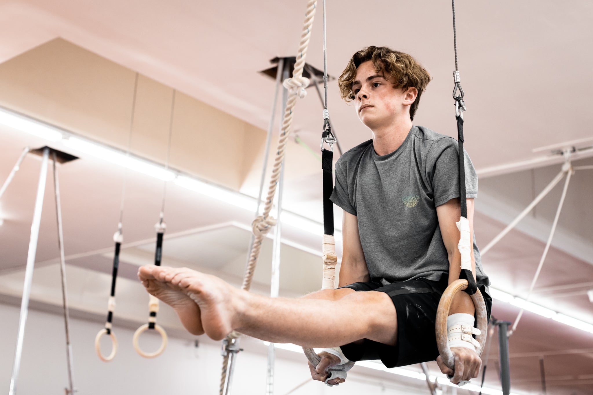 Male gymnast on rings wearing Reisport® Men's Hyper Protec Ring Grips on hands