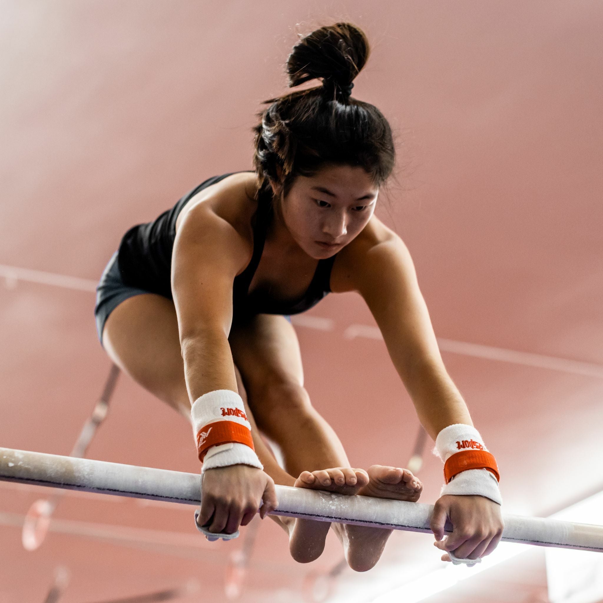 Female gymnast on uneven bars wearing Reisport® Women's Elite Protec Uneven Bar Grips