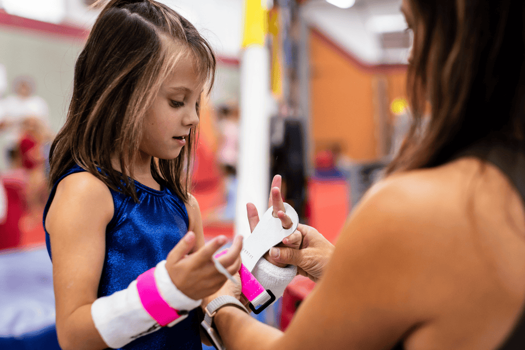 young girl getting help from coach putting on pink Gibson Rainbow grips
