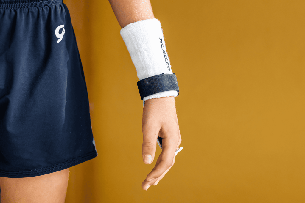 hand wearing black rainbow grip on yellow background