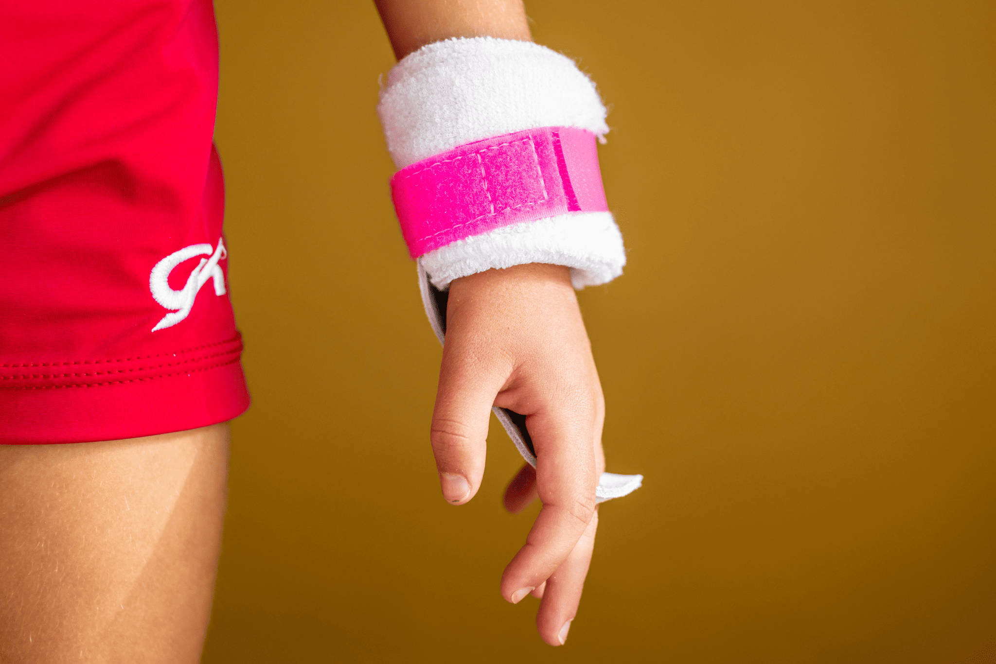 hand wearing pink rainbow grip on yellow background
