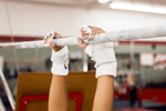 Gibson Summit High Bar double buckle grips on hands hanging from gymnastics bar