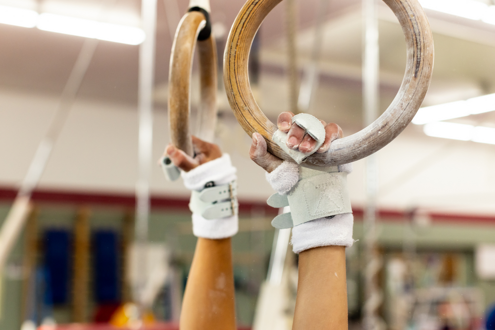 
                  
                    Load image into Gallery viewer, Gibson Summit Ring double buckle grips on hands hanging from gymnastics rings
                  
                