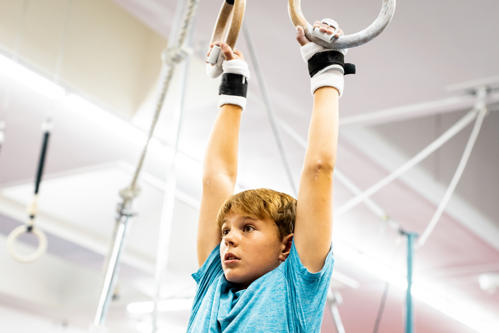 
                  
                    Load image into Gallery viewer, boy wearing Gibson Summit Ring hook and loop grips hanging from gymnastics rings
                  
                