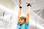 boy wearing Gibson Summit Ring hook and loop grips hanging from gymnastics rings