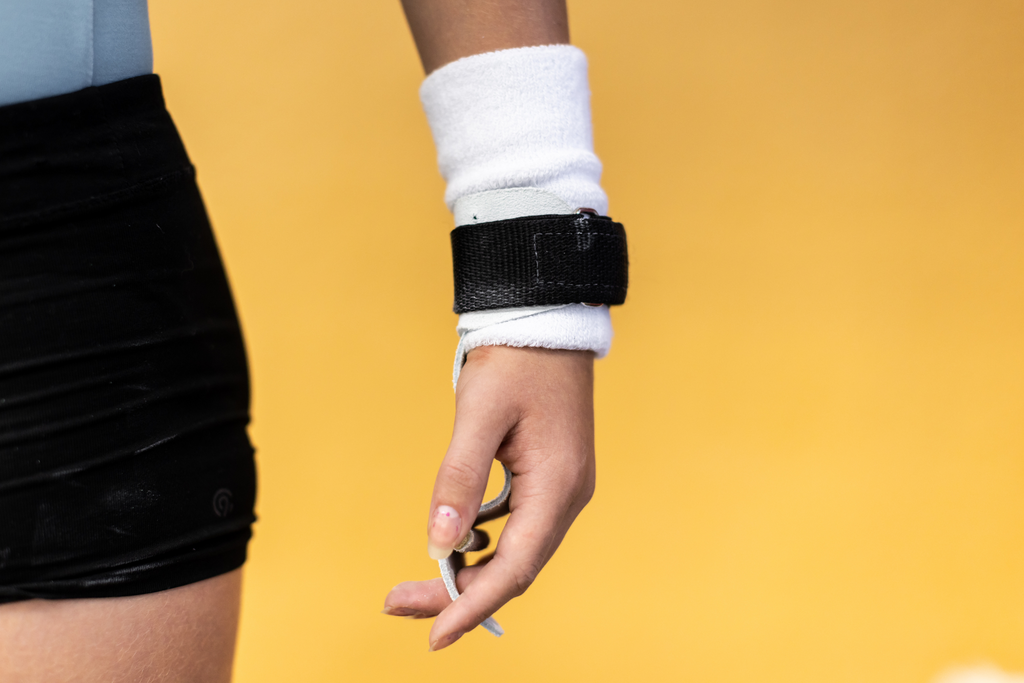 Gibson Summit Uneven Bar hook-and-loop grips on hand on yellow background