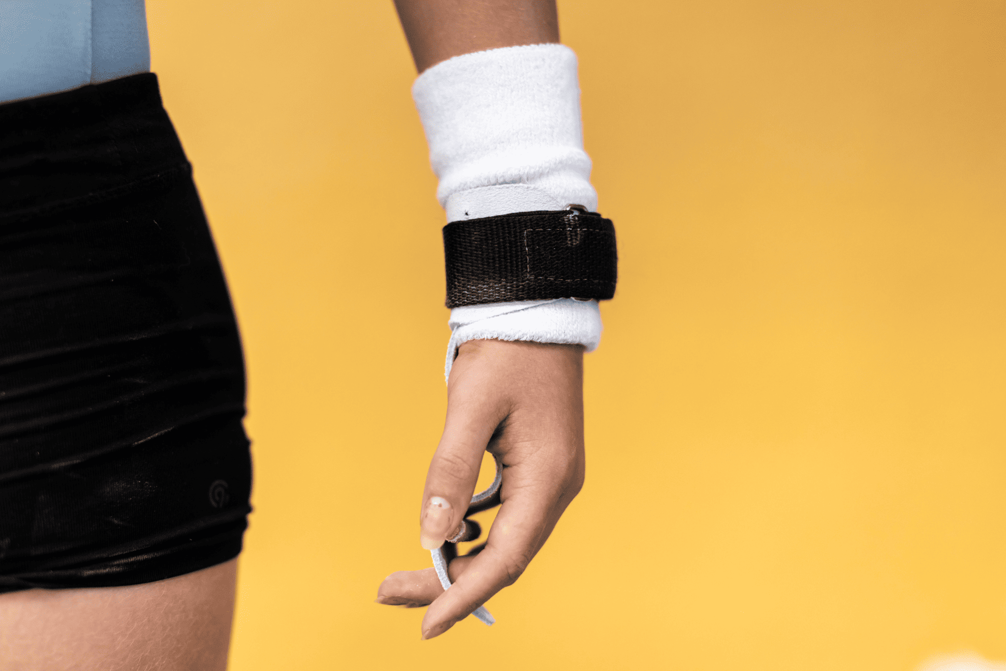 Gibson Summit Uneven Bar hook-and-loop grips on hand on yellow background