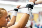 Gibson Summit Uneven Bar hook-and-loop grips on girl hanging from gymnastics bar